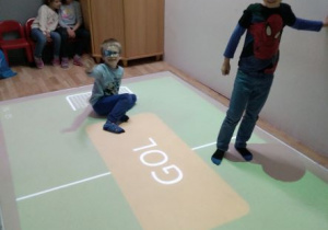 Chłopcy grają w grę Piłka nożna na podłodze interaktywnej